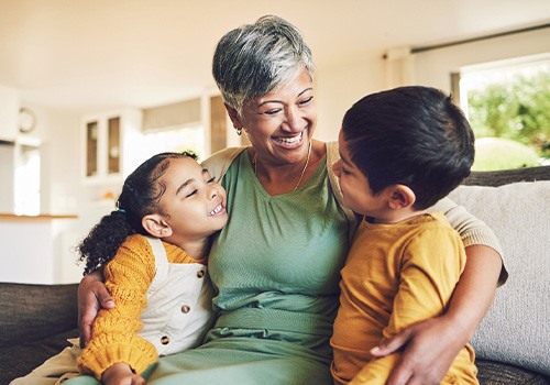 Woman in green shirt smiling down at children in yellow shirts