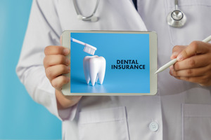 Dentist holding up tablet with the words “dental insurance”