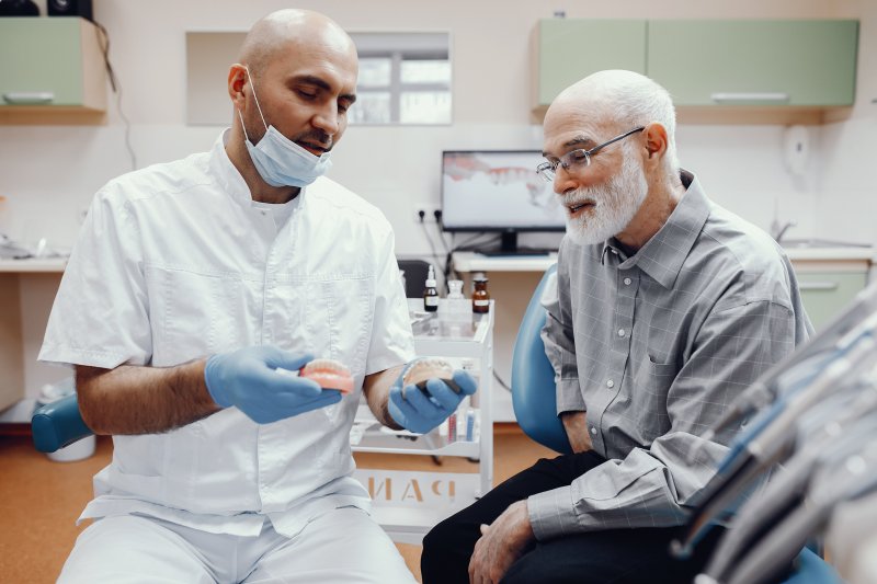 An older man talking to his dentist about full dentures